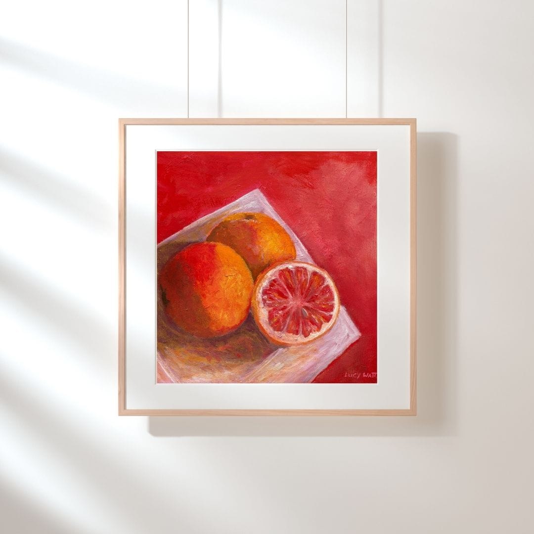 Lucy Watts Artwork still life framed print of ruby grapefruit on white plate with warm tones on white wall background. 