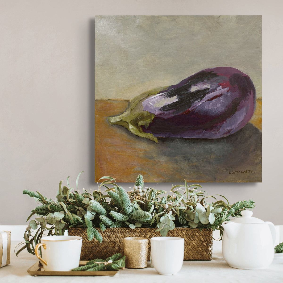 Painting of an eggplant on a wall above a table with plants and tea set.