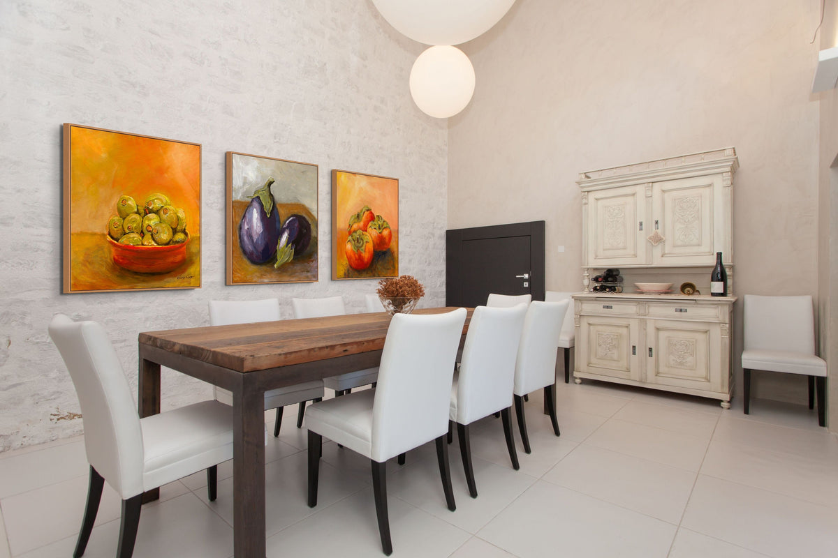 Dining room with a wooden table and white chairs, featuring wall art of fruit.