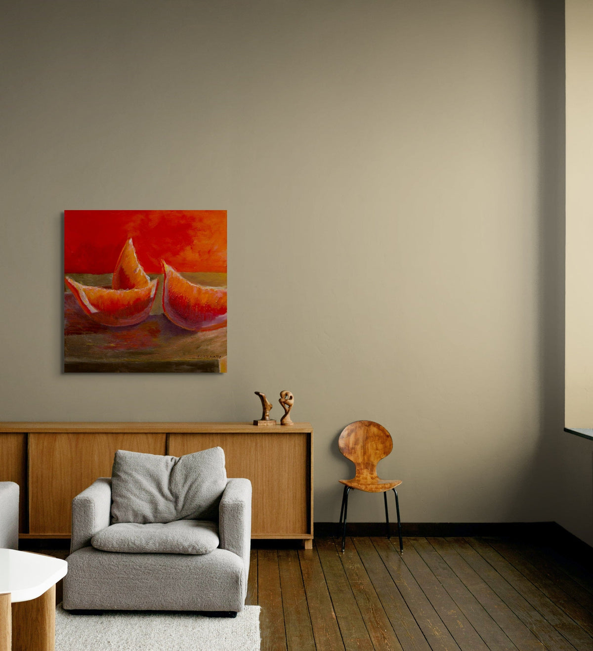 Living room with a painting of two boats on a wall, a gray armchair, wooden cabinet, and chair.