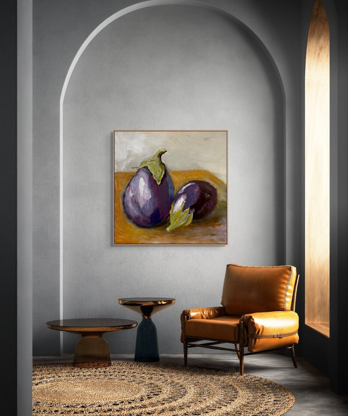Modern interior with a brown leather chair, round tables, and a painting of eggplants on a gray wall.