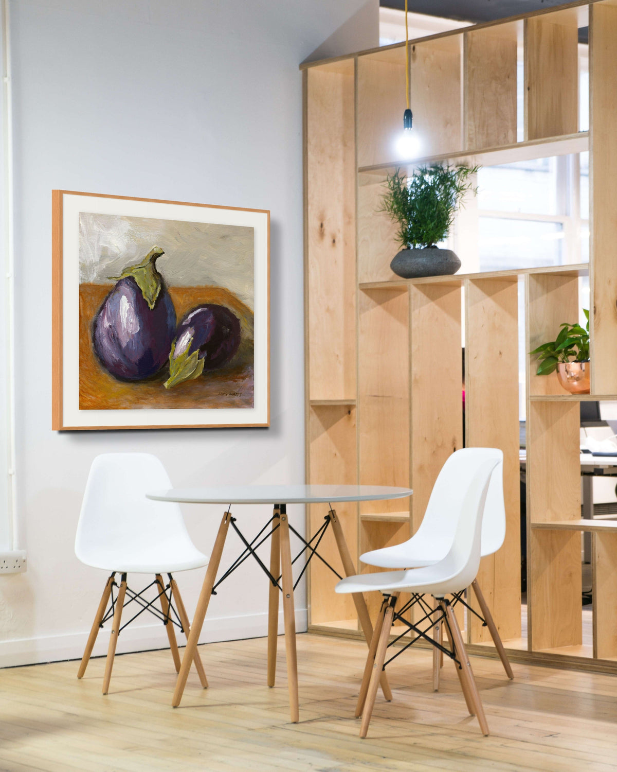 Modern dining area with white chairs, a round table, and a framed artwork on the wall.