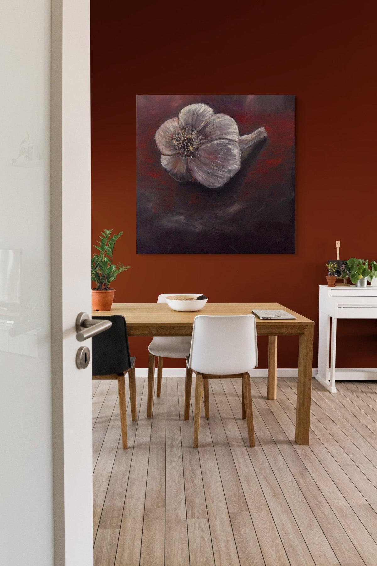 Dining room with a wooden table and chairs, a painting on the wall, and a plant.