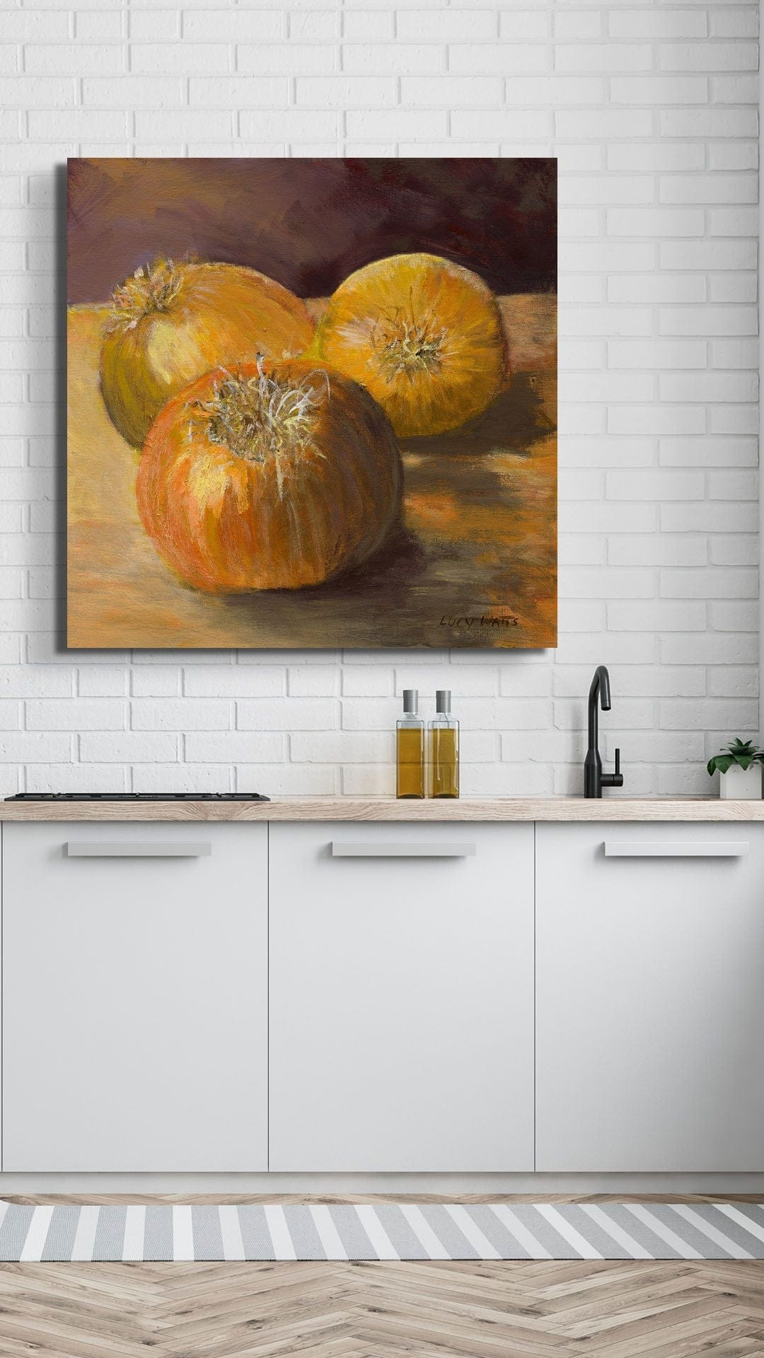Painting of pumpkins on a kitchen wall with white cabinets and a tiled backsplash.