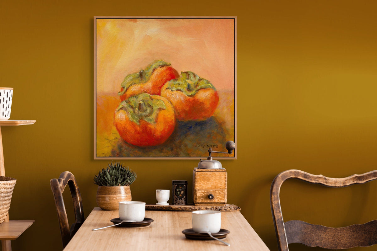 Dining room with a painting of persimmons on the wall, wooden table with cups and a plant.