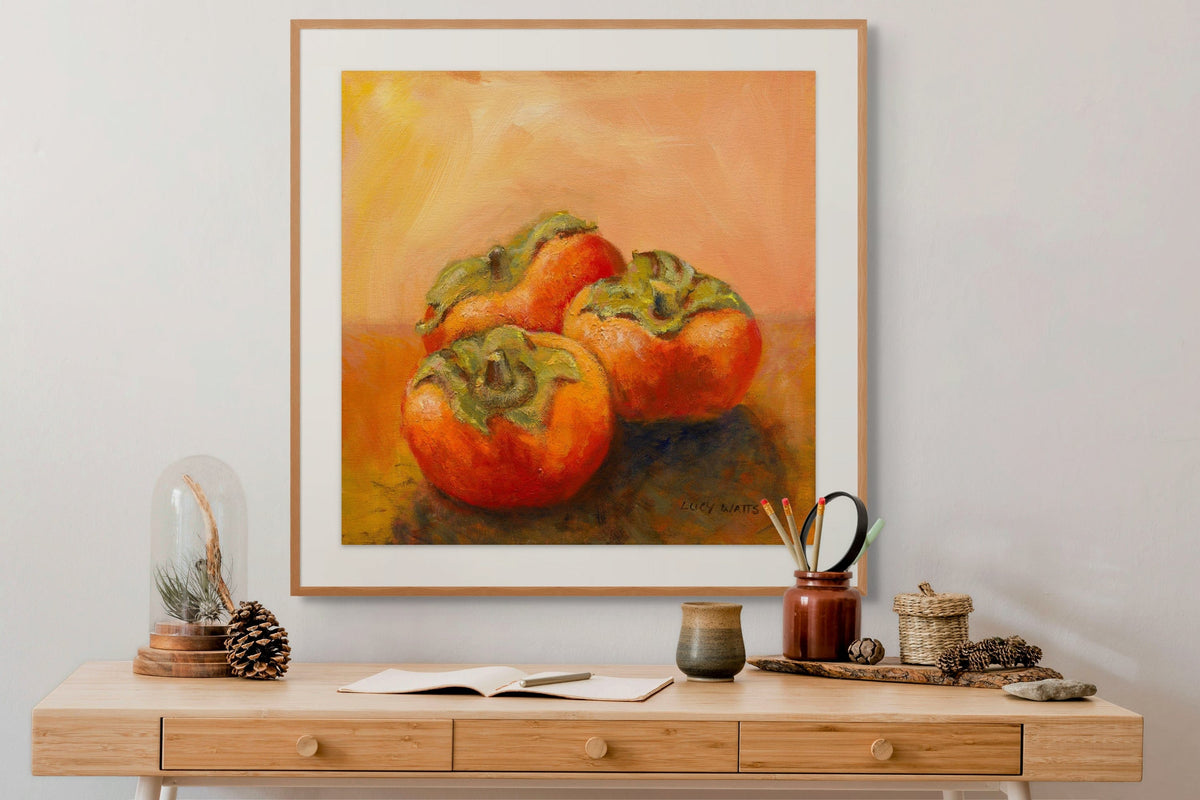 Framed artwork of persimmons on a wooden console table with decorative items.