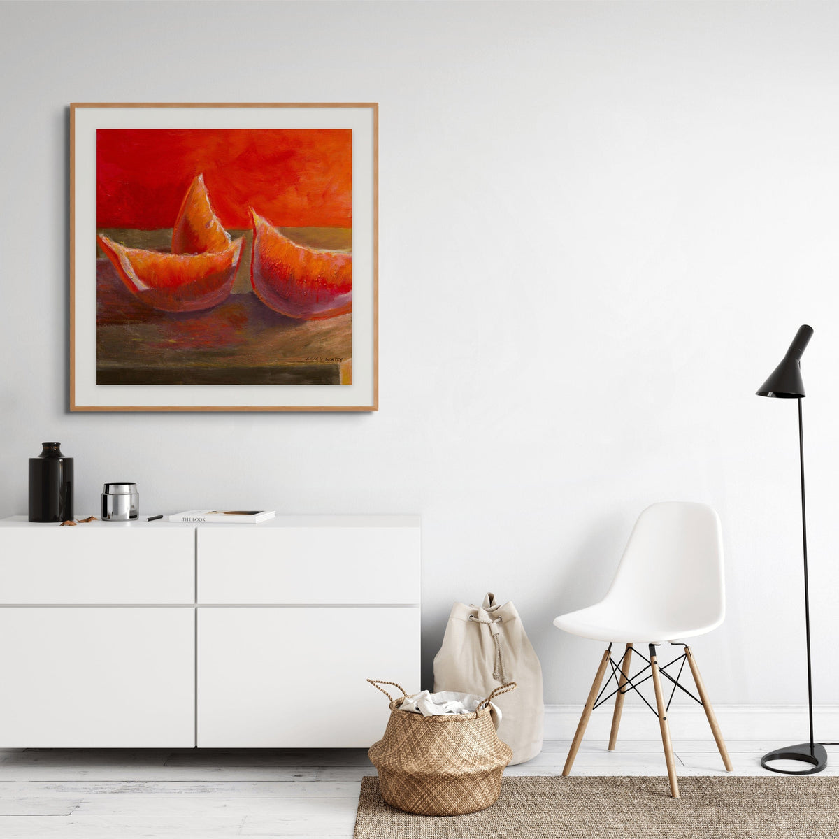 Modern living room with a white cabinet, white chair, and a painting of orange fruit on the wall.